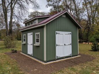 12x16 cottage with green wooden siding tan trim red metal roof and white doors